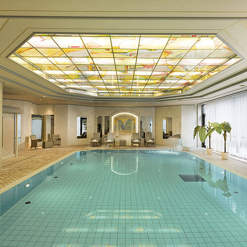  Indoor pool with skylight and loungers at the wellness area of the Maritim Hotel Ulm