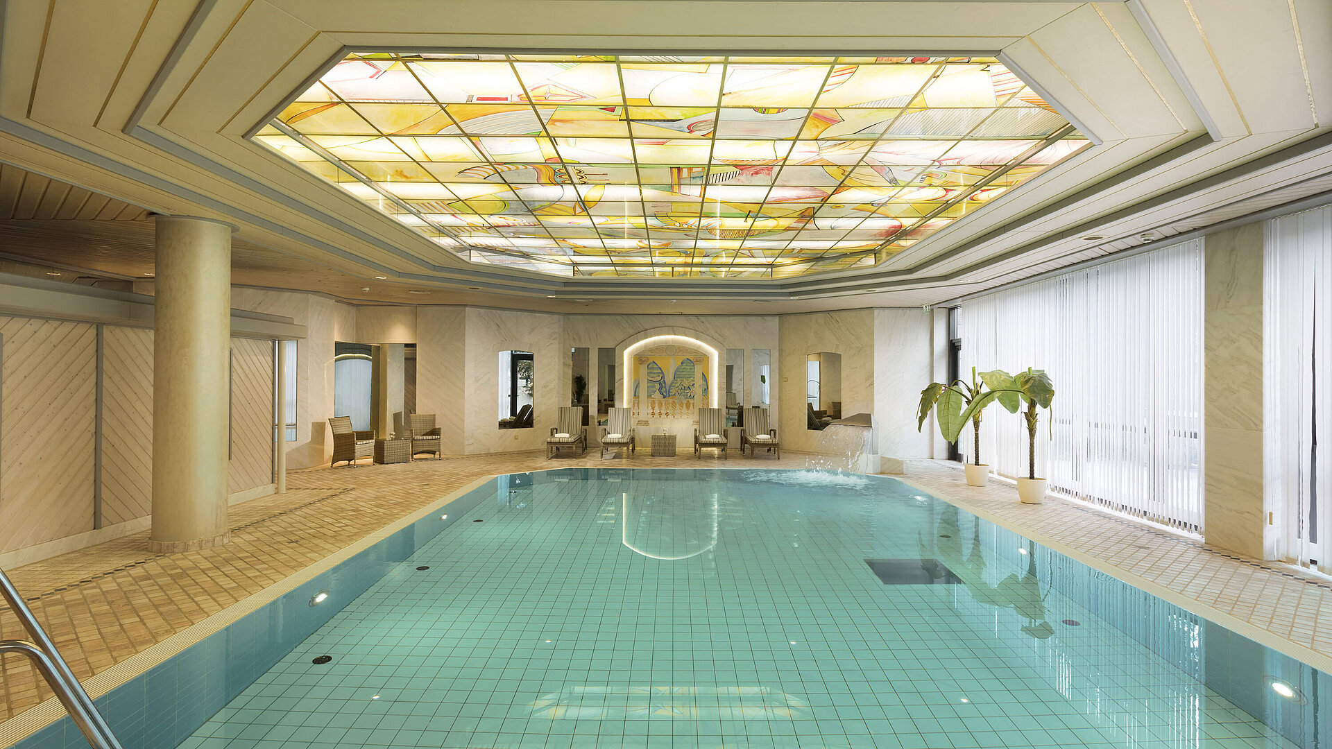  Indoor pool with skylight and loungers at the wellness area of the Maritim Hotel Ulm