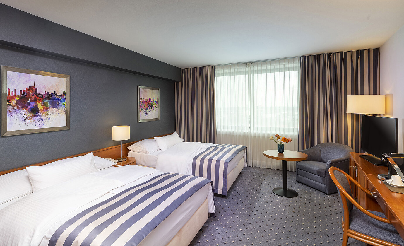Family room at Maritim Hotel Ulm with twin beds, TV and cosy seating area