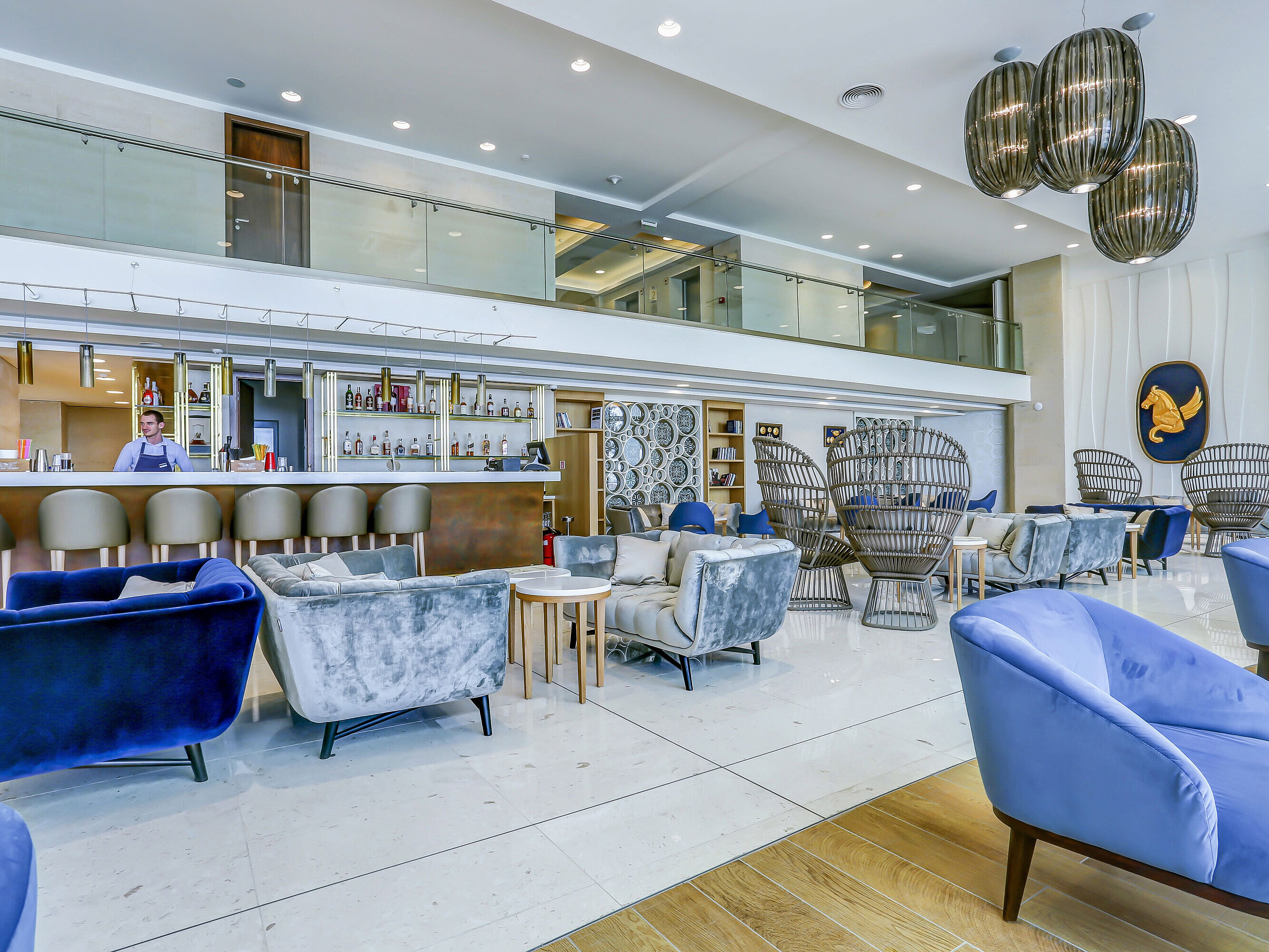 Modern hotel lobby with stylish seating areas, a large bar and elegant, bright interior design