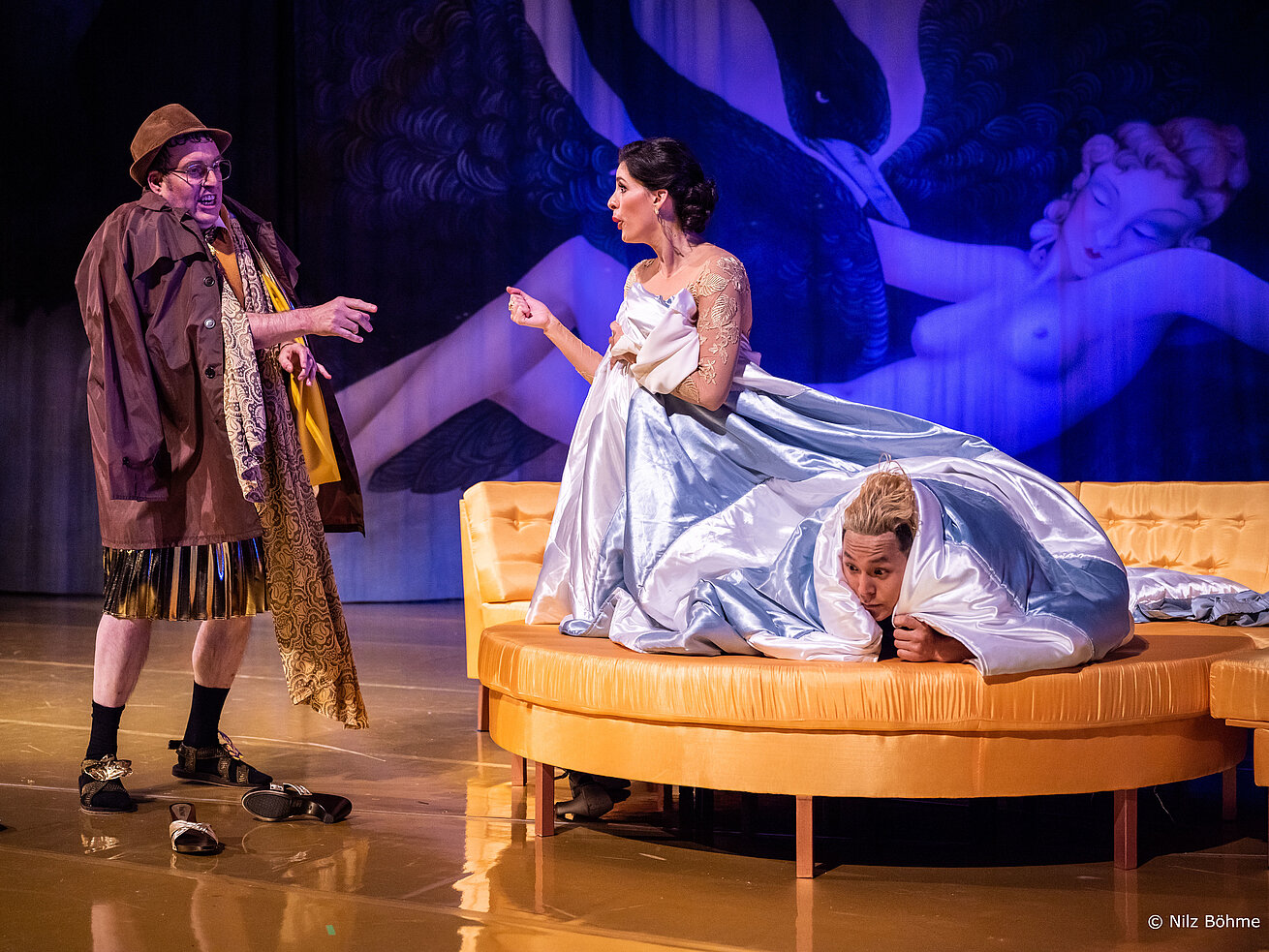 Opera scene with performers in historical costumes on a theatre stage during a live performance