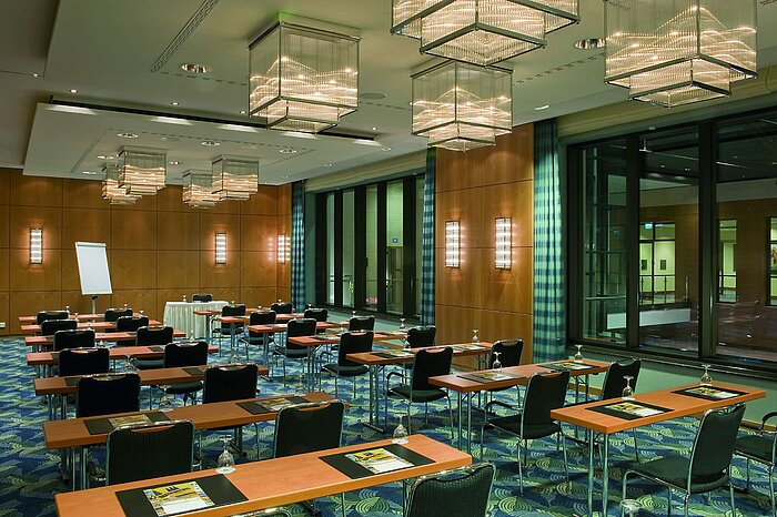 Modern conference room with elegant chandeliers, wooden walls, and large windows at the Maritim Hotel.