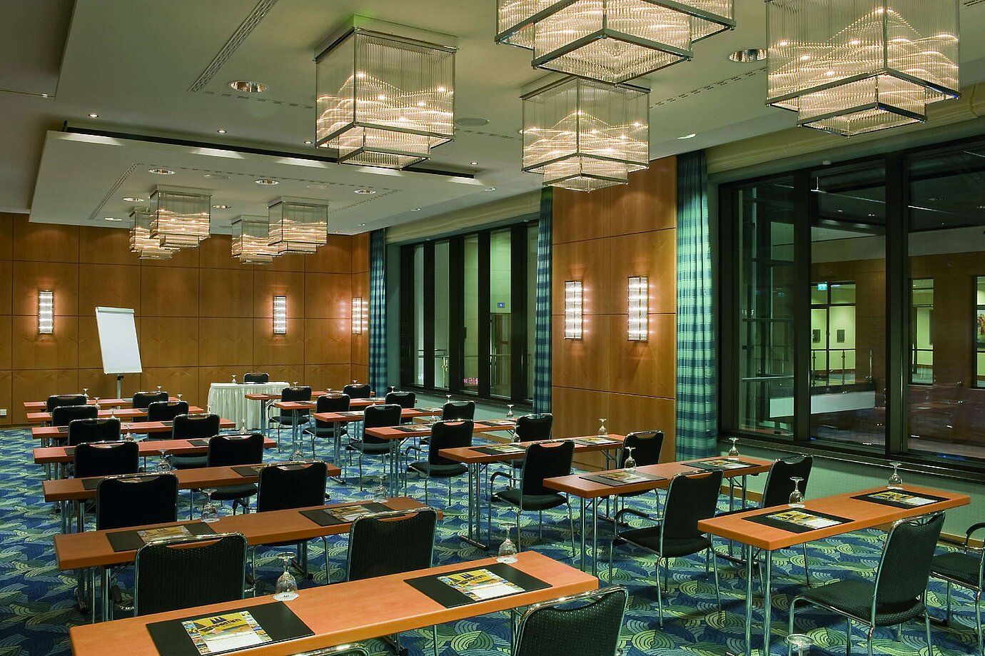 Modern conference room with elegant chandeliers, wooden walls, and large windows at the Maritim Hotel.