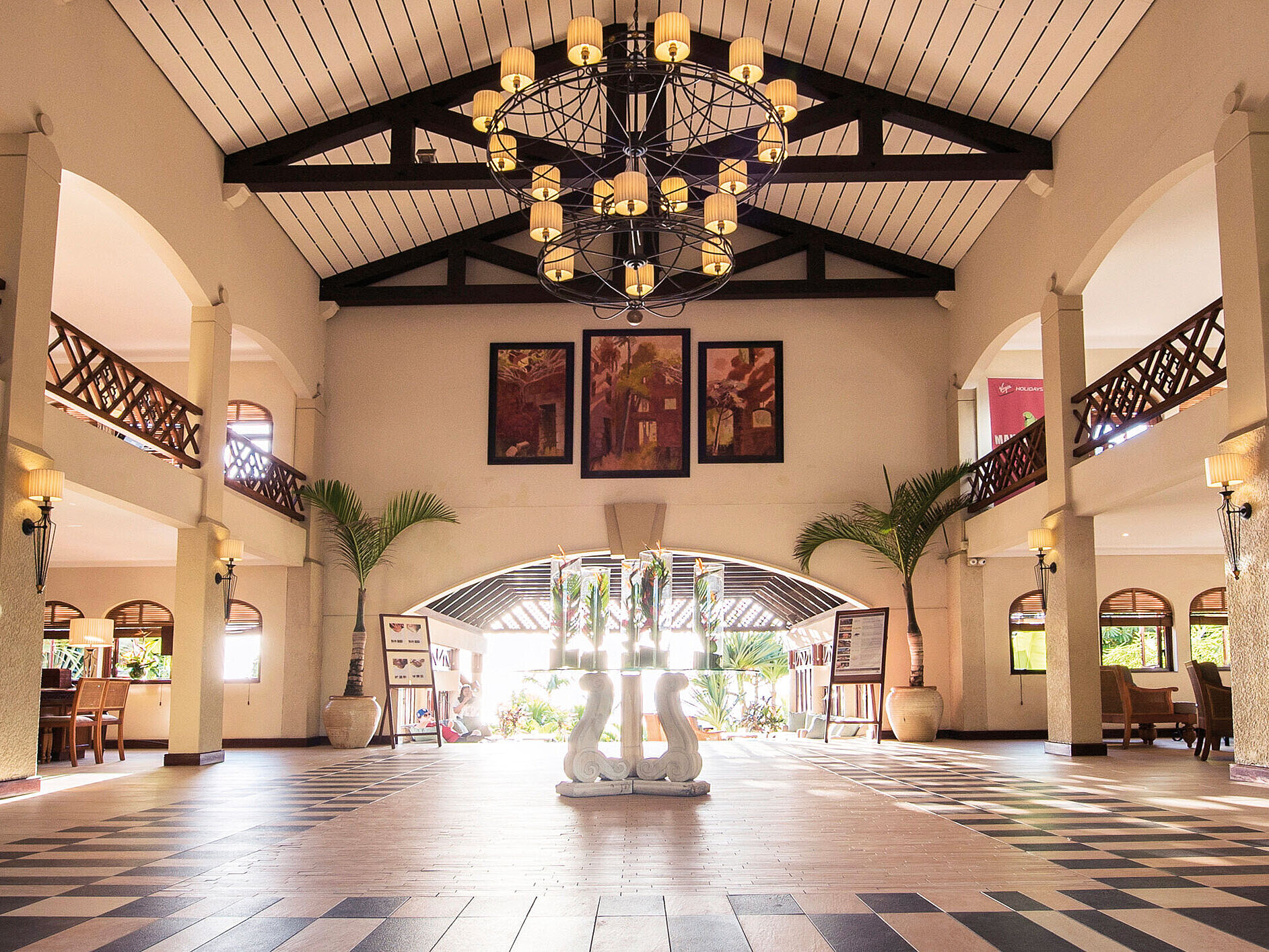 Spacious hotel lobby with gallery, chandelier, seating areas and open entrance
