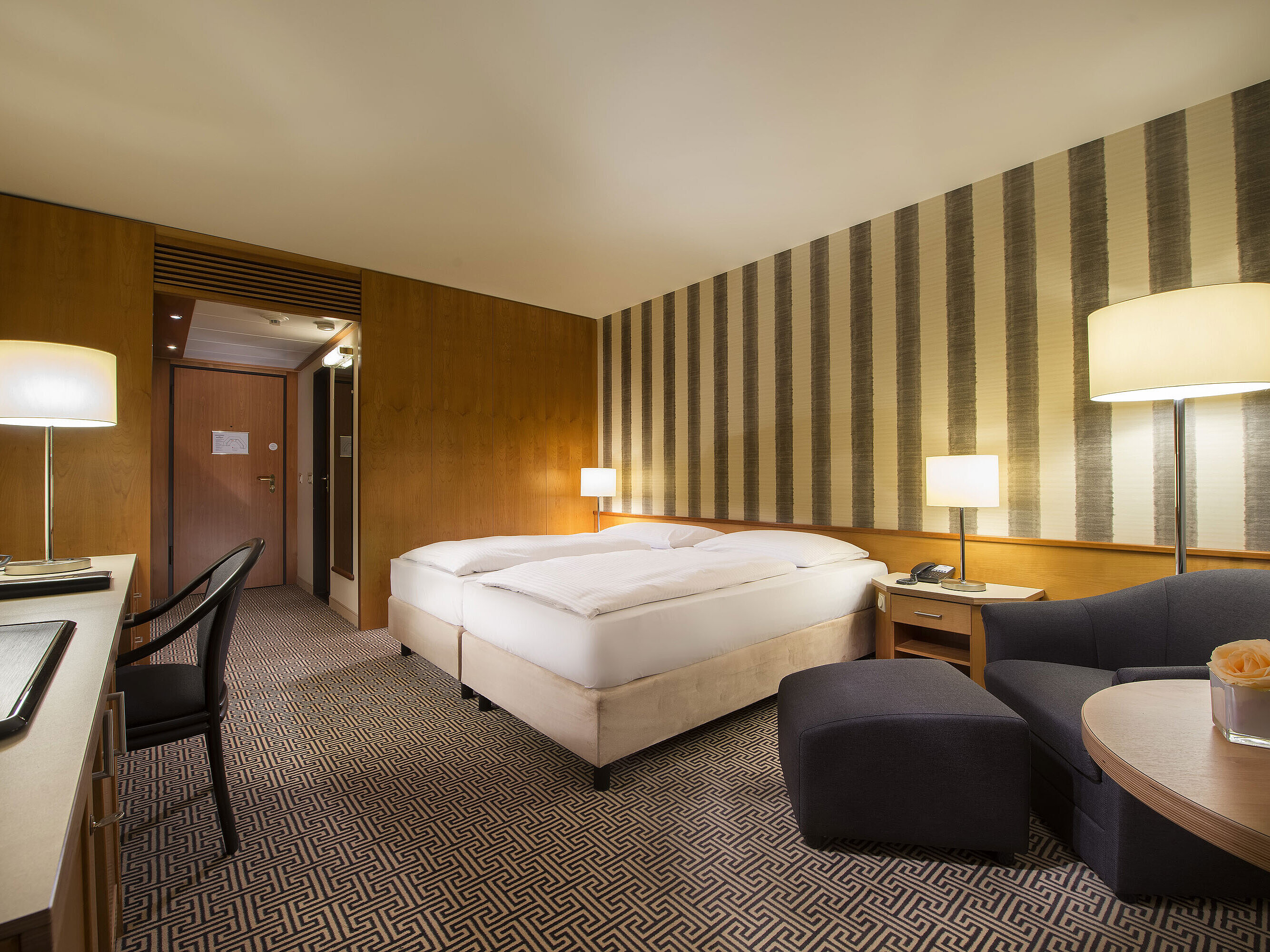 	Bright double room with soft lighting and cosy sitting area at Maritim Hotel Stuttgart