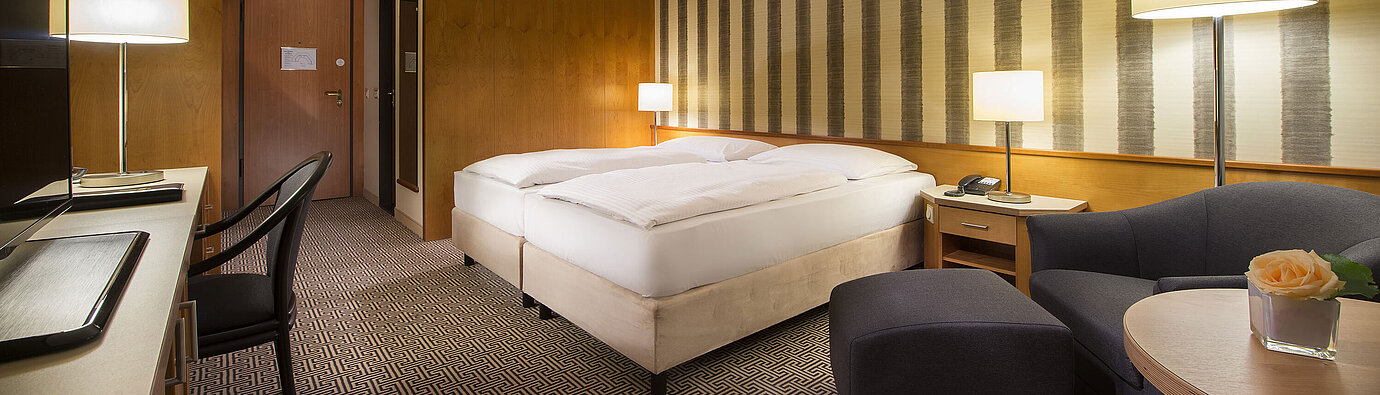 	Bright double room with soft lighting and cosy sitting area at Maritim Hotel Stuttgart