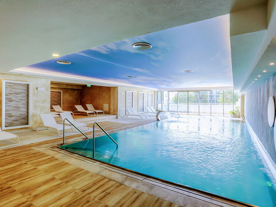 Bright indoor pool at the Maritim Hotel with modern loungers, large windows and a relaxing wellness atmosphere