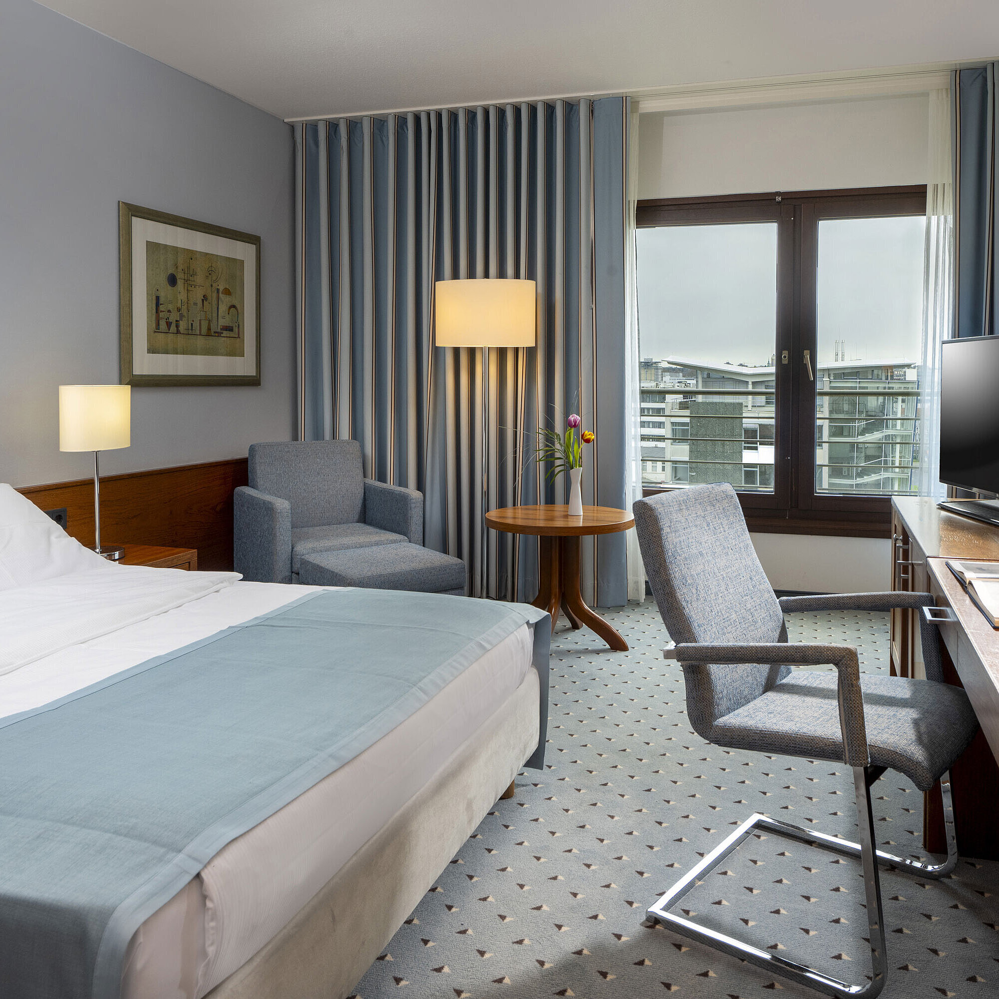 Comfort double room at Maritim Hotel Darmstadt with cozy seating area, modern desk, and city view.