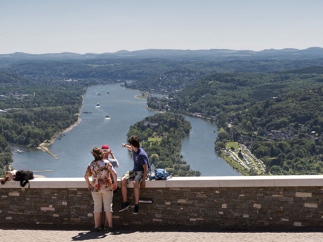 Visitors enjoy the breathtaking view from Drachenfels over the Rhine and surrounding forests.