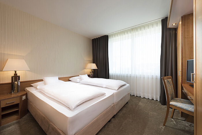 Bright double room at Maritim Hotel Stuttgart with desk, TV and cosy atmosphere