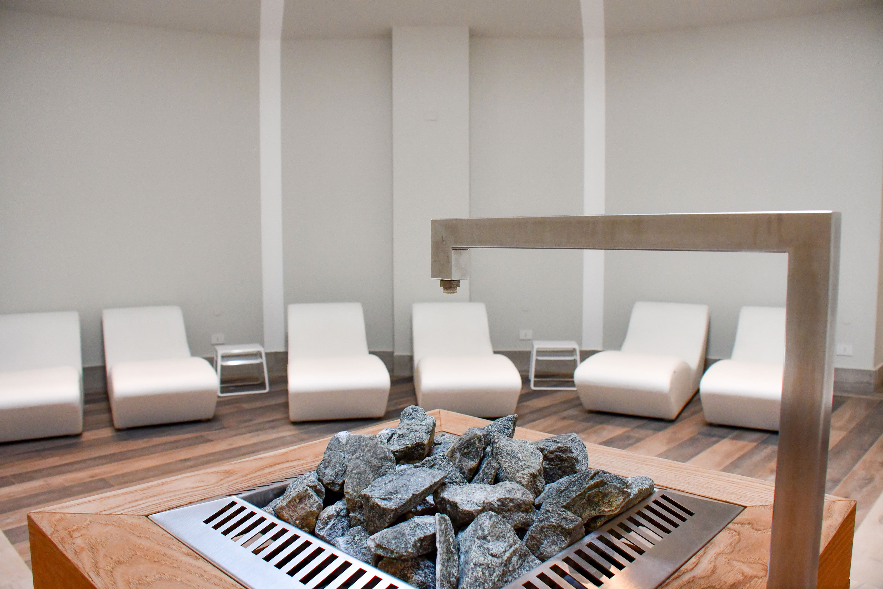 Modern relaxation room at Maritim Resort Calabria with loungers and central sauna heater for peaceful breaks.